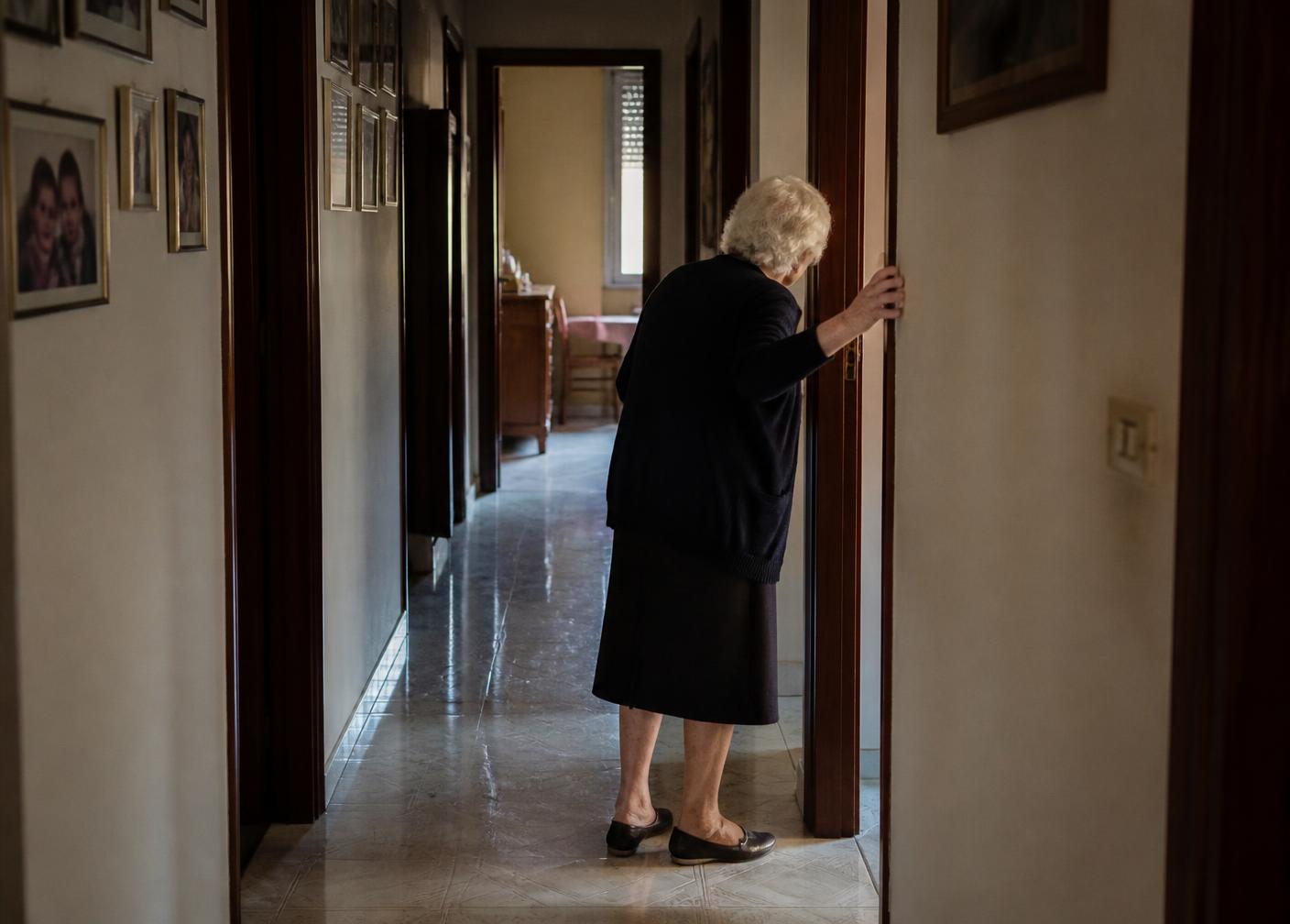 Un anziano aiutato ad alzarsi dalla poltrona nel soggiorno di casa